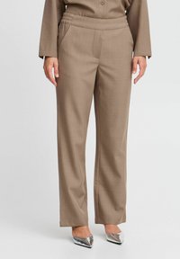 Pantaloni beige a palazzo con texture liscia, dotati di una vita elasticizzata e tasche laterali, abbinati a scarpe argento a punta.