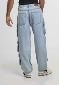 Lyseblå cargo-bukser lavet af denim, med store sidelommer og en afslappet pasform. Taljen har et lædermærke.