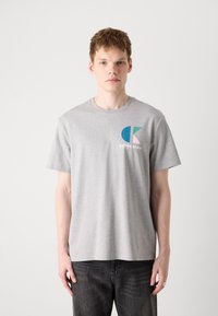Grå bomulds T-shirt med korte ærmer, rund halsudskæring, med et flerfarvet logo på venstre brystområde. Afslappet pasform, blød tekstur.