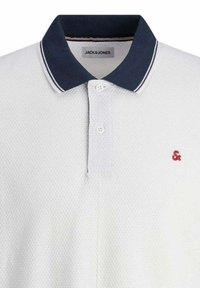 Polo bianco realizzato in un tessuto pi textured, con colletto blu navy e accento del logo rosso. Presenta due bottoni e bordino del colletto a righe in contrasto.