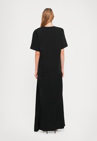 Black t-shirt with short sleeves, paired with a long black skirt. The fabric is smooth with a simple, streamlined design.