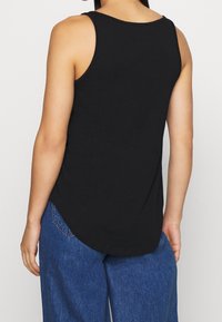 Top basic nero con orlo arrotondato, realizzato in morbido cotone. Design senza maniche con un taglio semplice e pulito sul retro.