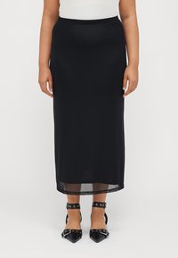 Black knee-length skirt made of smooth, lightweight fabric with an elastic waistband. Paired with pointed black heels featuring buckled straps.
