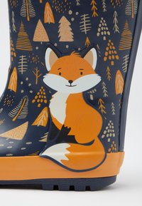 Botte de pluie en caoutchouc bleu avec des accents orange, ornée d'une illustration de renard. Décorée d'arbres et de points dans diverses couleurs et motifs.