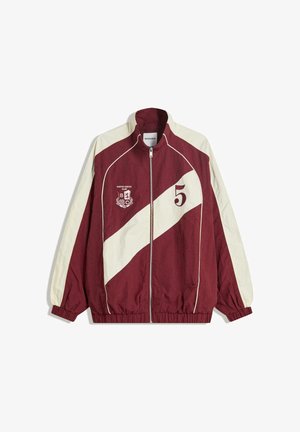 Maroónová a krémová zipsová bunda s vysokým golierom, elastickými manžetami a lemom. Obsahuje diagonálny pruhový dizajn a textové detaily.