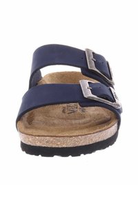 Sandale à glissière bleu marine avec deux boucles argentées ajustables, semelle intérieure en liège et semelle en caoutchouc noir texturé. Matériau supérieur en synthétique lisse.