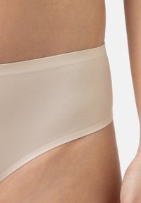 Perizoma in cotone beige con cintura elastica liscia e design senza cuciture, caratterizzato da una texture morbida.