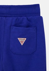 Koningsblauwe joggingbroek met een geribbelde tailleband, voorzien van een enkele achterzak met een rood-witte driehoekige logopatch.