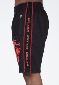 Schwarze Shorts aus strukturiertem Material, mit roten Seitenstreifen und dem Aufdruck "GORILLA WEAR." Inklusive einer mit Reißverschluss versehenen Tasche.