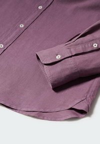 Camisa abotonada morada hecha de una tela suave, con un cuello puntiagudo, mangas largas y botones blancos. Textura lisa con dobladillo curvado.