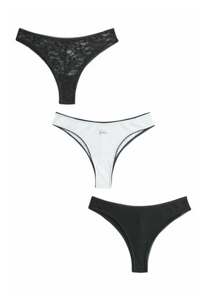 Trois tangas pour femmes, un en dentelle noire, un blanc avec bordure noire et texte, un noir uni avec texture côtelée, disposés verticalement sur fond blanc.