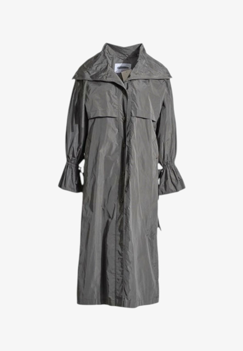 Long imperméable gris avec fermeture à boutons, large rabat de col et manches cloches froncées avec liens aux poignets.