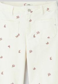 Pantalons en velours côtelé crème clair avec broderies florales en rose et accents marron, dotés de deux poches arrière et d'une fermeture à bouton à la taille.