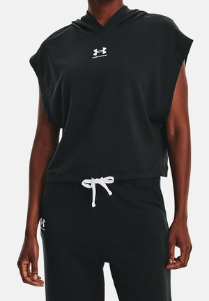 Aikuinen, jolla on musta hihaton huppari ja siihen sopivat mustat narupuvun housut, joissa valkoiset Under Armour -logot rinnassa ja reidessä.