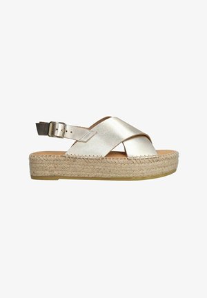 Metalen gouden espadrille sandaal met kruislings banden, verstelbare enkelgesp en geweven jute platformzool. Glad textuur en casual ontwerp.