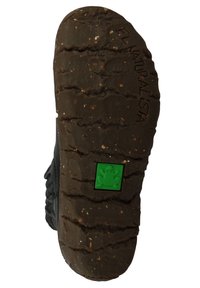 Black rubber shoe sole with deep tread pattern, featuring a green frog logo. Textured surface with small specks and uneven edges.
