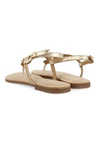 Sandali piatti color oro con cinturini intrecciati, dettagli in fibbia e una soletta beige con texture, poggiati su una suola color marrone chiaro.