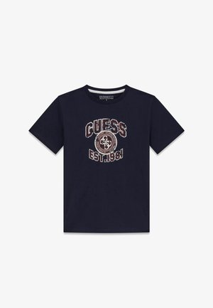 T-shirt à manches courtes bleu marine foncé avec le texte « GUESS EST. 1981 » et un logo circulaire en blanc usé et marron au centre devant.