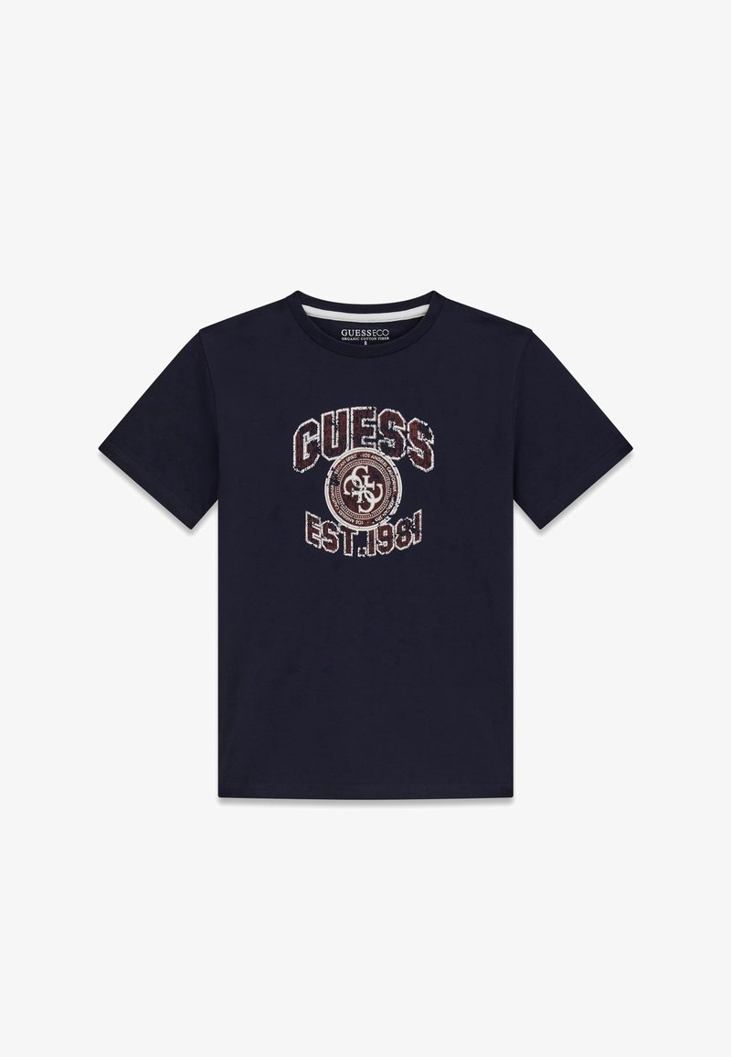 T-shirt à manches courtes bleu marine foncé avec le texte « GUESS EST. 1981 » et un logo circulaire en blanc usé et marron au centre devant.