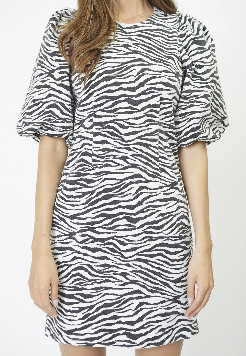 Vestido de manga corta en una tela suave, con un patrón de rayas de cebra en blanco y negro, escote redondeado y dos bolsillos frontales.