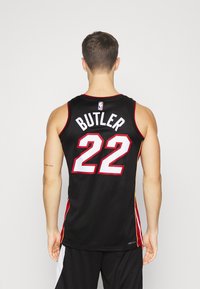 Crna NBA majica s crvenim i žutim bočnim akcentima. Na leđima se nalazi ime "BUTLER" i broj "22" u podebljanoj bijeloj boji.