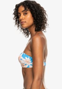 Blå bandeau-bikinitopp med palmebladmønster i lys beige, med rynkedetaljer og en glatt tekstur på stoffet.