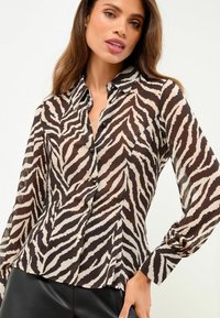 Transparante overhemd met knopen in een zwart en beige zebrapatroon, met lange mouwen, een klassieke kraag en een getailleerde taille.