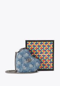Sac en denim en forme de cœur avec un design matelassé, de couleur bleue, et une bandoulière en chaîne argentée. Comprend un emblème de couronne décoratif. La boîte présente un motif coloré.