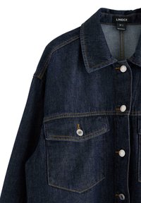 Mörkblå denimjacka med klassisk krage, silverfärgade knappslutningar, två bröstfickor och kontrasterande gul sömnad.