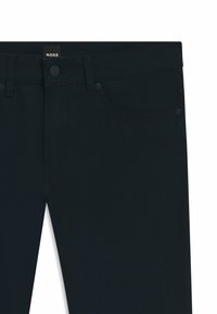 Donkerblauwe spijkerbroek met een standaard vijf-pocket ontwerp, knoopsluiting en contrasterende stiksels. Zachte textuur en moderne pasvorm.