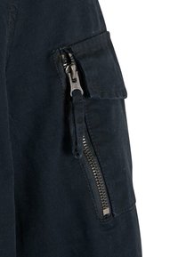 Black fabric with a textured finish featuring a silver zipper and a side pocket, highlighting practicality in design.