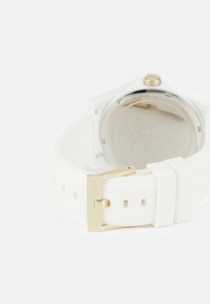 Reloj de silicona blanco con caja de acero inoxidable y detalles en tono dorado. Cuenta con una correa texturizada, cierre de hebilla y detalles grabados en la parte posterior.