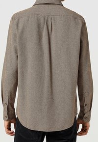 Brązowo-czarna koszula w kratę z kołnierzykiem zapinanym na guziki, długimi rękawami i plisą z tyłu; tkanina wydaje się mieć fakturę.