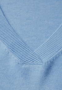 Hellblauer Strickpullover mit V-Ausschnitt und Rippendetails am Kragen. Weiche Textur mit einem feinen, gleichmäßigen Maschenmuster.