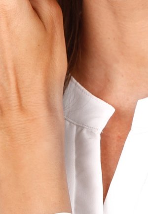 Gros plan d'une main touchant le cou, avec une chemise blanche à col visible.