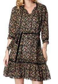 Svart blommig klänning med färgglad bladmönster, trekvart ärmar, volangkant och ett svart bälte som framhäver midjan.