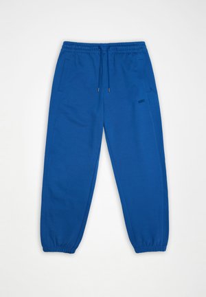 Blue elastic waist sweatpants with drawstring, side pockets, elastic cuffs, and small "RAINS" logo on the right thigh.