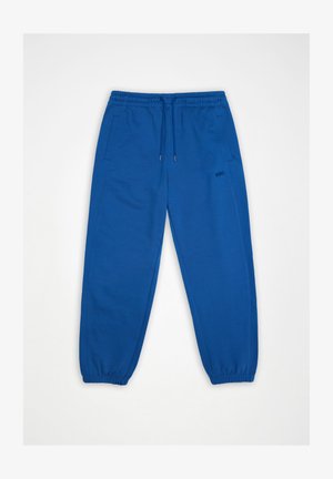 Mėlynos elastinės liemens sportinės kelnės su raišteliu, šoninėmis kišenėmis, elastinėmis rankogaliais ir mažu „RAINS“ logotipu dešinėje šlaunies pusėje.