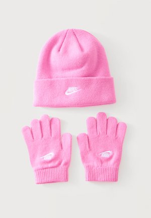 Bonnet en tricot rose Nike et gants assortis avec logos blancs brodés sur un fond clair uni.