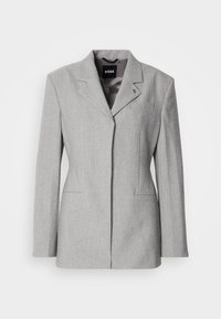 Γκρι μάλλινο σακάκι με δομημένους ώμους, κλείσιμο με ένα κουμπί και δύο μπροστινές τσέπες. Διαθέτει πέτο με εγκοπές και διακριτικό λογότυπο μάρκας.