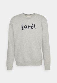 Lichtgrijze sweatshirt met lange mouwen en ronde hals, voorzien van geribde manchetten en zoom, met het woord "forét" in het zwart geborduurd op het midden van de voorkant.