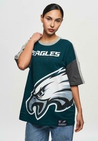 Vihreä ja harmaa ylipitkä t-paita, jossa on kotka-graphic ja "EAGLES"-teksti. Valmistettu sileästä kankaasta, lyhyillä hihoilla ja rentolla leikkauksella.