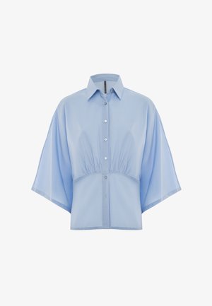 Camicetta corta azzurro chiaro realizzata in un tessuto morbido, con maniche corte e larghe, colletto a punta e cinque bottoni sulla parte anteriore.