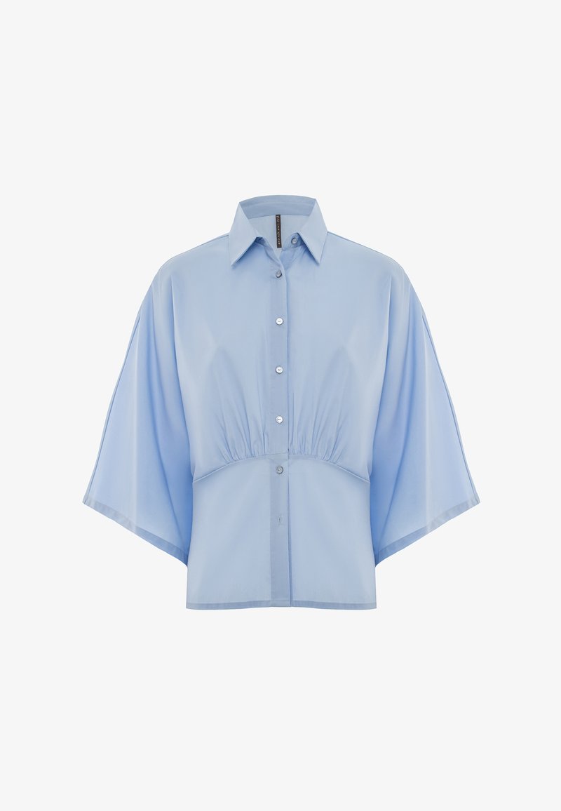 Camicetta corta azzurro chiaro realizzata in un tessuto morbido, con maniche corte e larghe, colletto a punta e cinque bottoni sulla parte anteriore.