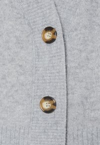 Cardigan grigio a maglia con polsini a coste e scollatura a V, accentuato da due bottoni rotondi marmorizzati marroni anteriormente.