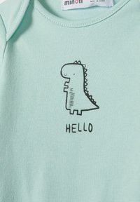 Világos menta zöld bébi overál puha pamutból, fekete dinoszaurusz grafikával és "HELLO" felirattal. Kerek nyakkivágás és rövid ujjú.