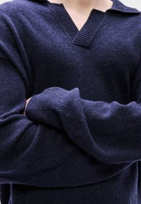 Πλεκτό πουλόβερ σε σκούρο ναυτικό μπλε, με V-λαιμόκοψη και ribbed γιακά. Φαρδιά μανίκια με απαλή υφή και χαλαρή εφαρμογή, που προσφέρουν ζεστασιά και άνεση.