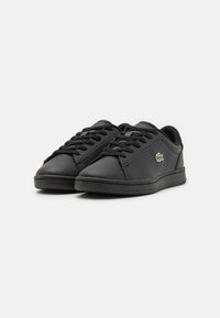 Sneakers in pelle nera con punta rotonda, chiusura con lacci, colletto imbottito e suola in gomma testurizzata. Presentano un piccolo logo sul lato.