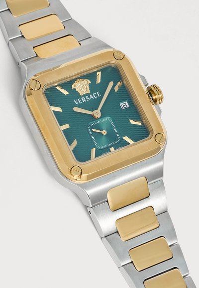 Montre-bracelet carrée Versace avec bracelet en métal doré et argenté, cadran vert, index dorés, affichage de la date et logo Méduse à 12 heures.