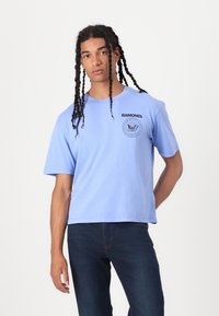 Light blue cotton t-shirt with short sleeves, round neckline, and black printed 'RAMONES' logo along with a graphic detail on the chest.